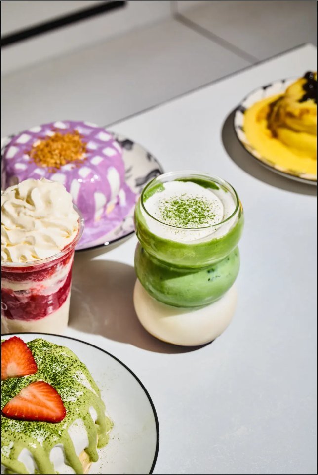 Taro dessert, strawberry cream cup, matcha latte and matcha soufflé pancakes on a white table