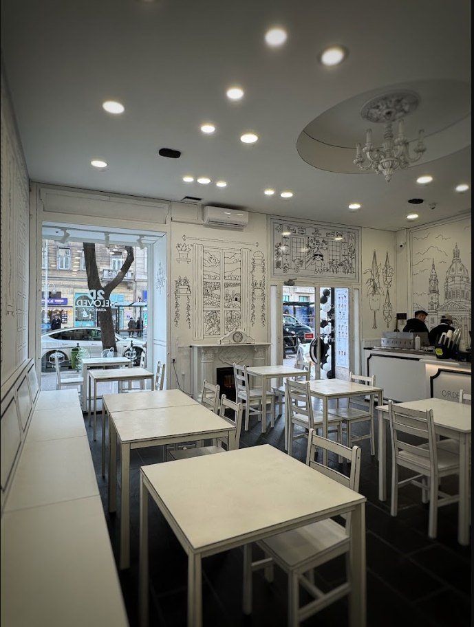 Hand-drawn black and white interior of 2D Café Beloved Budapest, with white outlined tables and chairs, a drawn chandelier on the ceiling and St Stephen's Basilica sketched on the wall