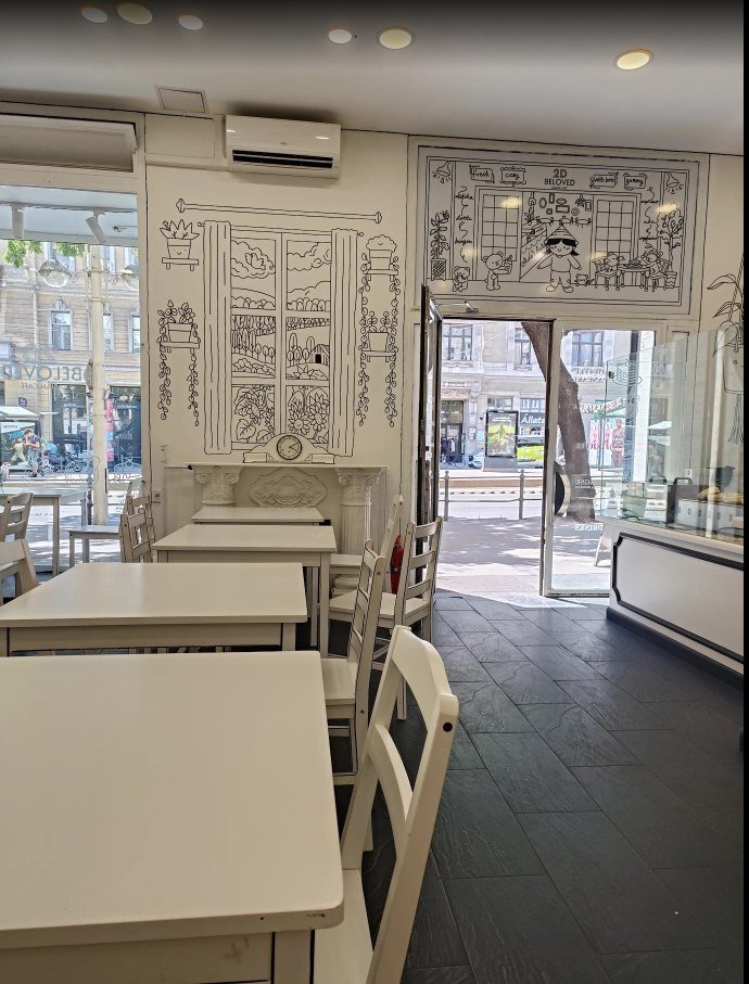 A window, shutters, plants and a mantel clock drawn in black line on the white wall of 2D Café Beloved, beside the real street window
