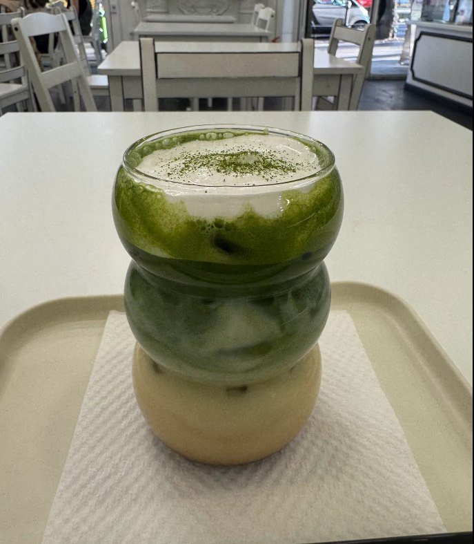 Matcha latte in the signature stacked glass, layered green matcha over milk and dusted with matcha powder