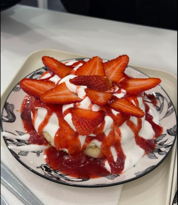 Strawberry Japanese soufflé pancakes with whipped cream, strawberry purée and fresh sliced strawberries, served on a patterned plate at 2D Café Beloved Budapest
